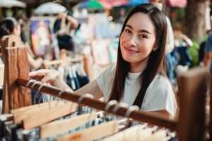 Beautiful Asian woman looking at clothes on clothing rack outside a store