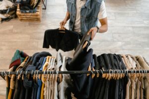 Person Replenishing the Clothes Hanging on the Rack not using loglife plastic hangers