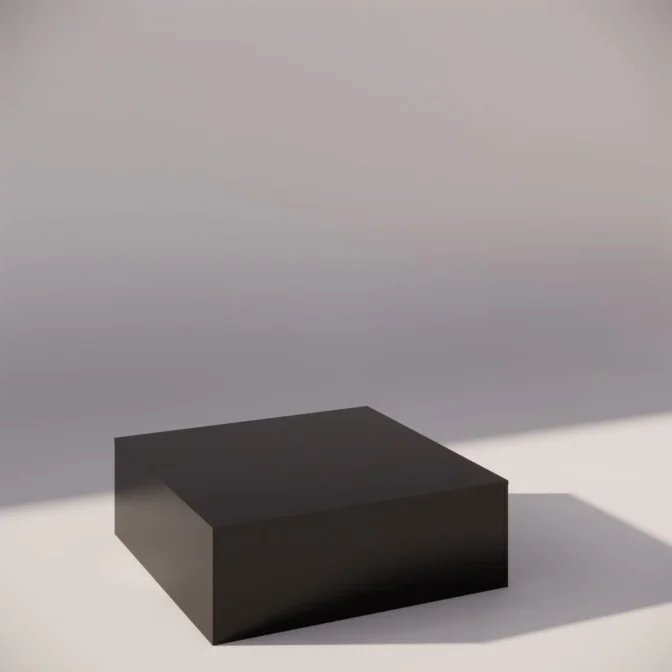 A black cube rests on a light gray surface, casting a shadow to the right. The cube is centered in the image, with soft lighting creating a minimalist and modern aesthetic.